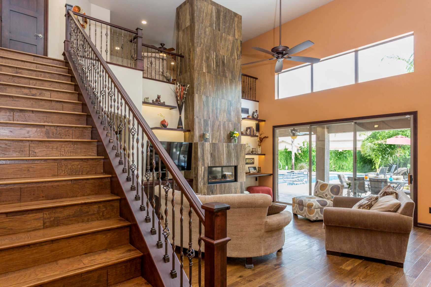 Spacious living room showing stairs to upper floor with balcony overlooking living area.