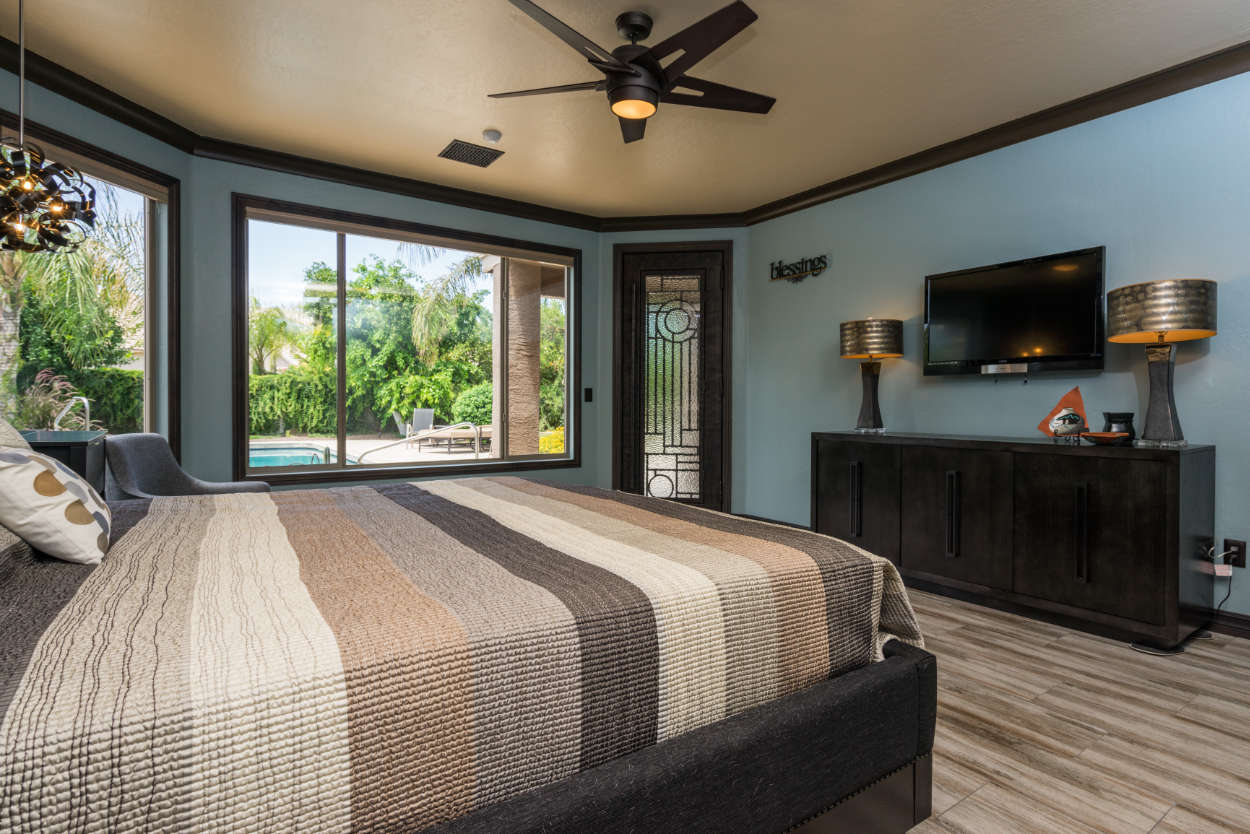 Teal and brown bedroom with large windows.