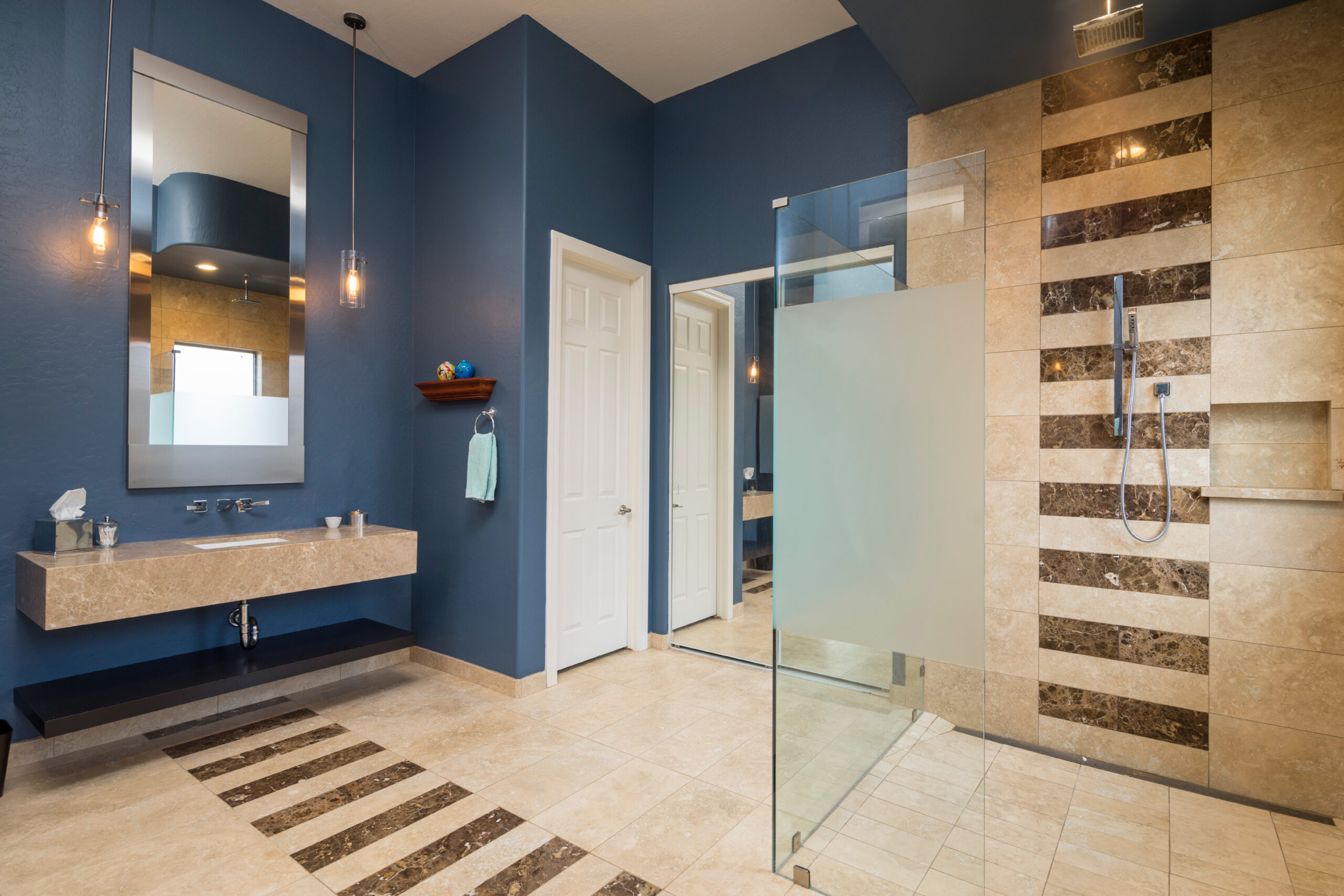 Tan, tiled bathroom with matching tiled shower and blue walls.