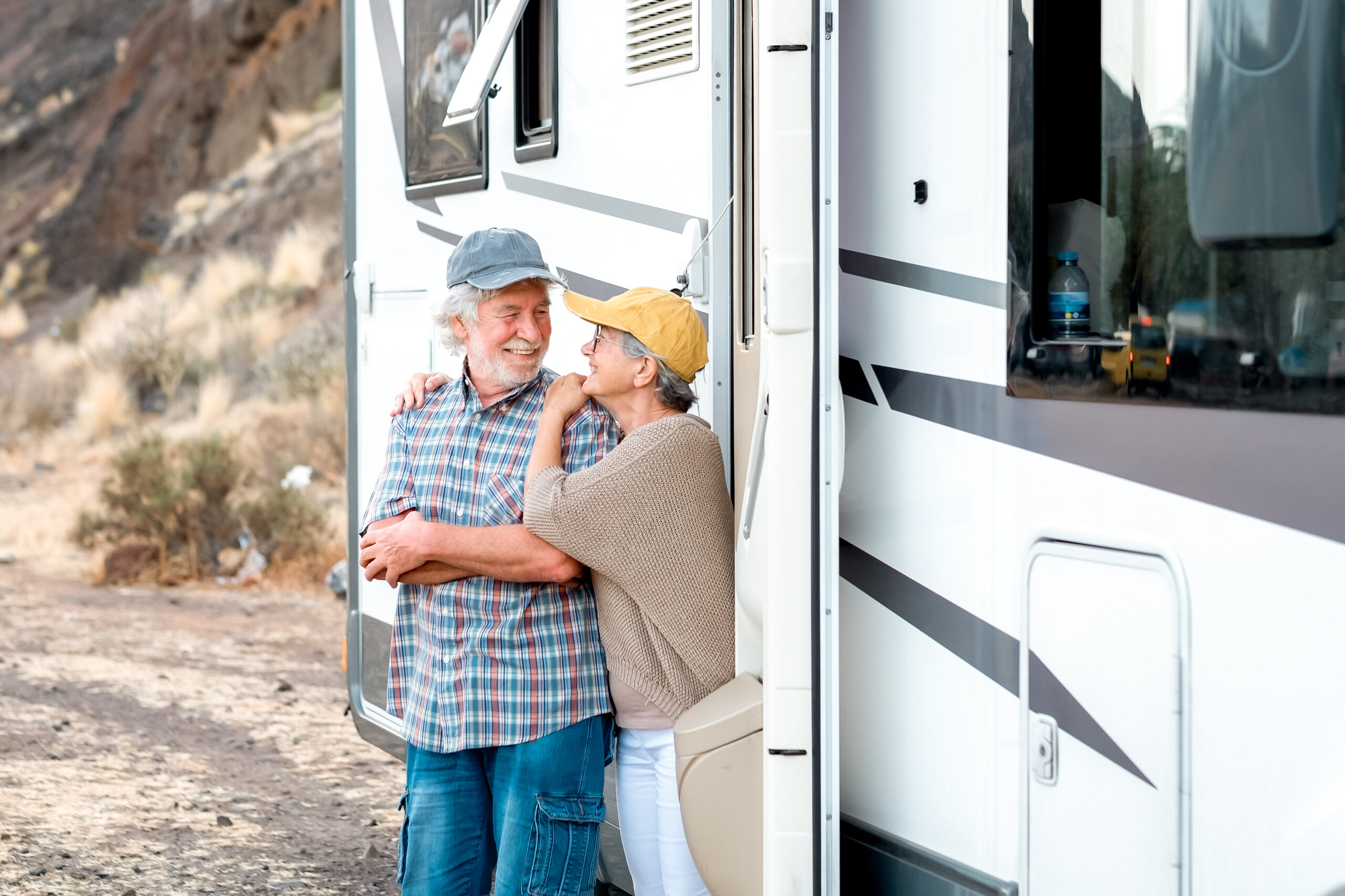 A happy senior couple standing outside an RV camper